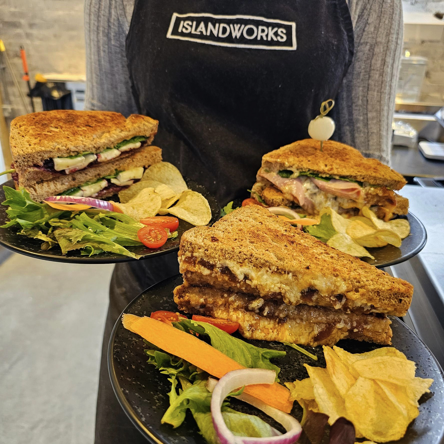 A photo of 3 freshly-made sandwiches available at IslandWorks, featured left to right; Brie & Cranberry, Chicken, Chorizo & Pesto, and Ploughman's with Plum Chutney.